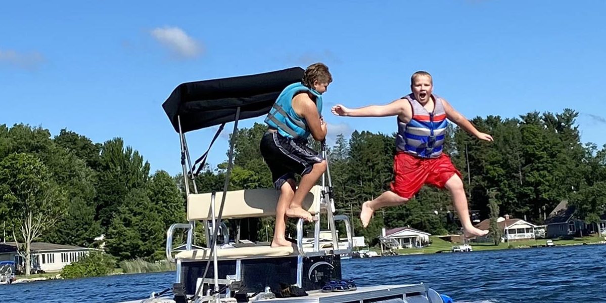 young boy jumping from boat into water at Gateway Park Campground in MI Top 5 Reasons Gateway Park Campground is Perfect for Families